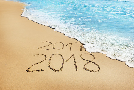 Digits 2017 and 2018 on the sand seashore- concept of New Year and Xmas and passing of timeの写真素材