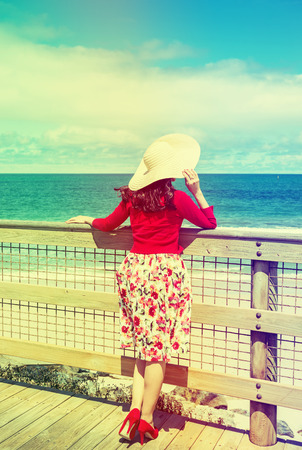 beautiful woman in red standing and looking to the sea  in retro styleの写真素材