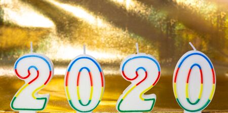 Christmas golden background with white numbers 2020 in the form of candles