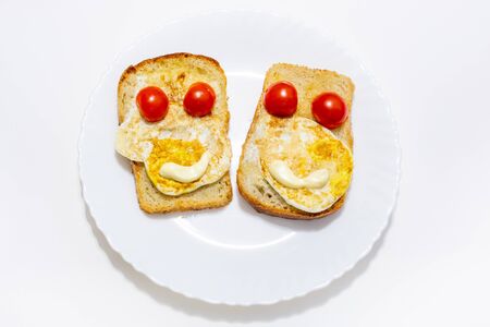 two muzzle-shaped sandwiches with egg and tomato for breakfast, lie on a white plate