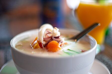 spicy coconut thai tom kha soup with a spoon in a bowl,blurred backgroundの写真素材