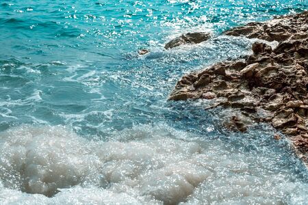 blue sea with foam from the waves and rocky shore