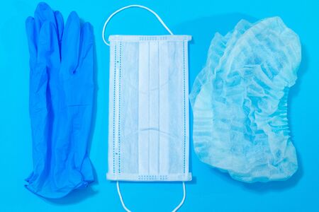 medical mask, gloves and hat on a blue background, personal protective equipment