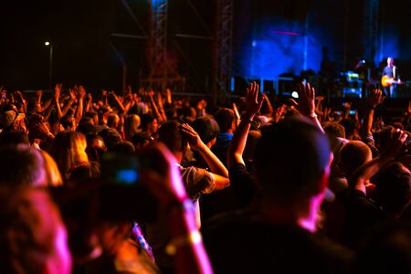 crowd of people with arms raised in the red light of lights