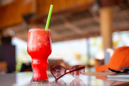 Watermelon smoothie in a glass with straws, stands on the table, soft drink on a summer day