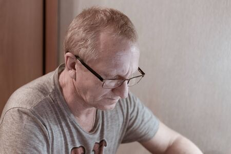 an elderly man with glasses lowered his head down and carefully reads