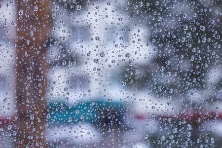 cityscape, blurred background behind wet glass with raindrops, seasons autumn