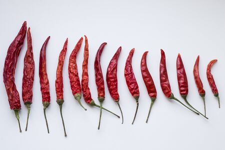 dry red hot peppers lying on a gray background in descending order, , seasoning for cookingの写真素材