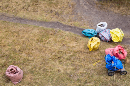 Kogalym, Russia - 05.04.2020:cleaning the yard with a rake, on the ground are bags of garbage and leaves, top viewのeditorial素材