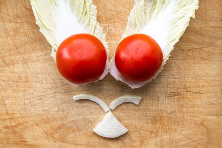 vegetables on a cutting board are laid out in the shape of a muzzle, tomatoes and cabbage for a vegetarian spring salad, healthy tasty foodの写真素材