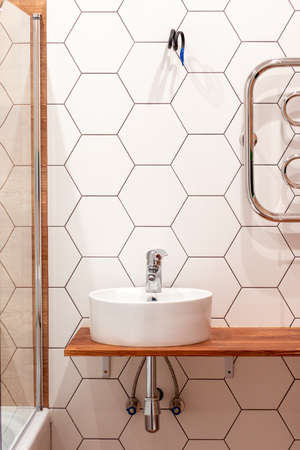 a round white sink with a mixer in the bathroom against a background of white tiles in the form of a...