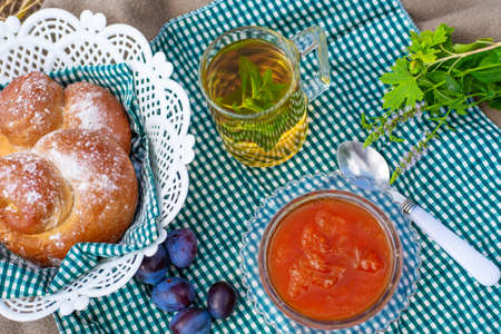 outdoor tea drinking. Mug of green mint tea, berry jam and freshly baked pastries. Summer pleasureの写真素材
