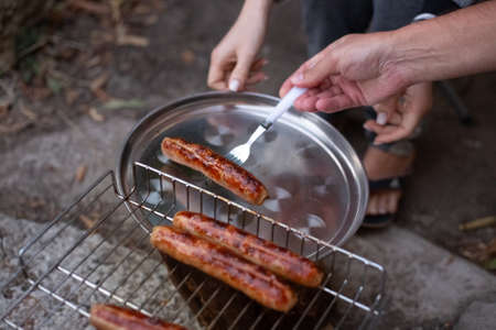 Grilled meat sausages. The man lays out the finished sausages on an iron tray. Oktoberfest.の写真素材