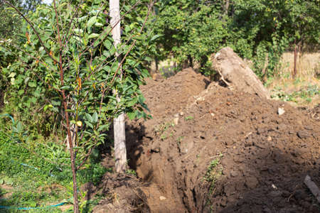 A ditch dug by an excavator in the ground in a village for laying a water supply system. Residential water supply.の写真素材