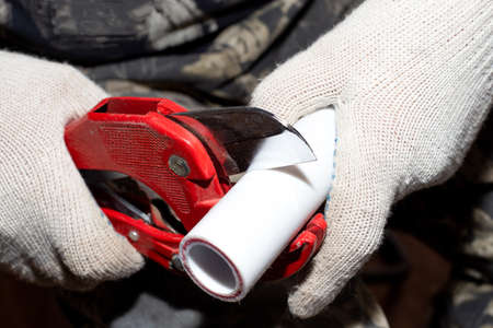 plumber cuts off a polypropylene pipe for plumbing installation, close-up.