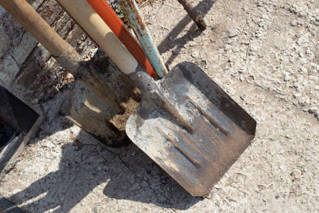 Old iron shovels against the wall in the street. Working garden tool.