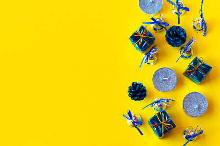 Christmas composition. Candles and Christmas decorations in blue on a yellow background. Flat lay, top view, copy spaceの写真素材