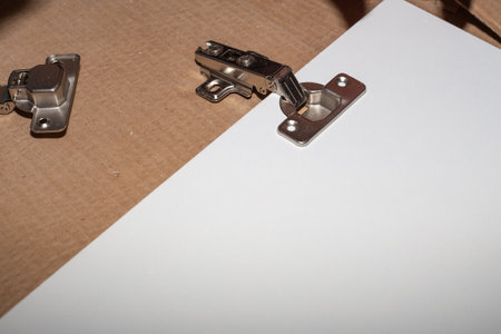 assembly of wooden furniture, metal hinge on the white cabinet door of the kitchen unit. Carpenter...
