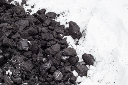 Coarse coal in the snow in winter. Maintaining high temperatures in fuel boilers, home heating systems. Combustible mineral.の写真素材