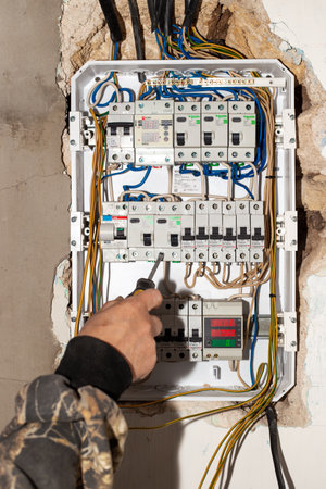 Anapa, Russia-07.11.2020: Electrical switchboard. A male electrician installs a multifunctional shield to control electricity into the wall of the house.のeditorial素材