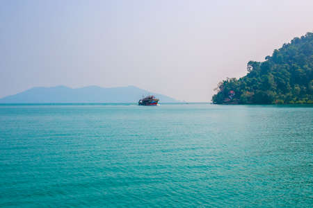 Beautiful tropical landscape. A ship sails across the blue sea, mountains overgrown with vegetation...