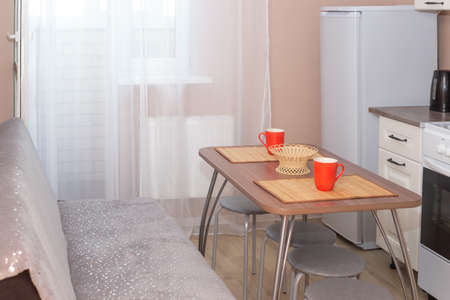 Kitchen interier. Wooden table in the center of the room with utensils. Household appliances and recreation areas.の写真素材