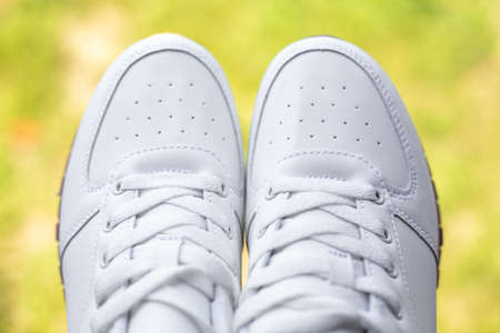 White sneakers on a background of green grass close-up. Sports fashionable shoes. Travel and Hiking.の写真素材