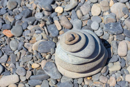 Round flat stones stacked in a pyramid on a pebble sea beach, top view. Copy space. Travel and tourism concept.の写真素材