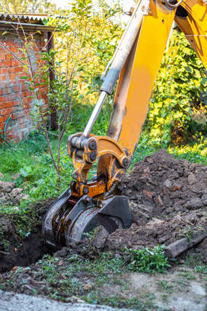 A tractor digs a trench with a bucket to lay a water supply system. Preparation for laying water...