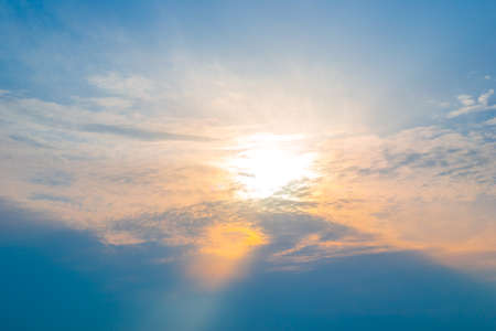 Sun in the clouds at sunset. The sunbeam illuminates the sky in orange.の写真素材