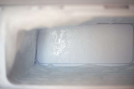 Frozen fridge freezer with ice. Household appliances care.の写真素材