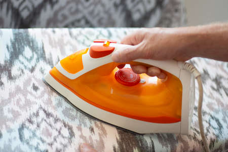 A man ironing linen with an electric iron on an ironing board. Help around the house.の写真素材