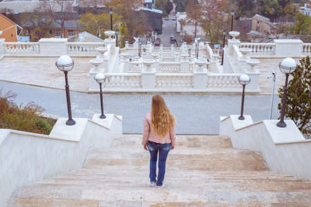 A woman with long blond hair descends a high white staircase in the Crimea in Kerch. Observation deck. Travel and tourism.の写真素材