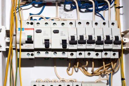 Electrical panel with toggle switches and wires. Installation of lead-in electricity to the house.