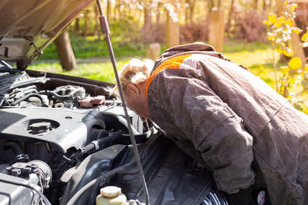 The man bent over the hood of the car and looks for a breakdown. Car repair and maintenanceの写真素材