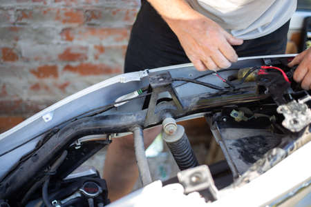 A man is repairing a motorbike. Disassembled motorcycle.
