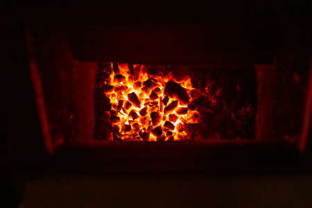 Burning coals in a solid fuel boiler. Heating of a residential building in winter.の写真素材