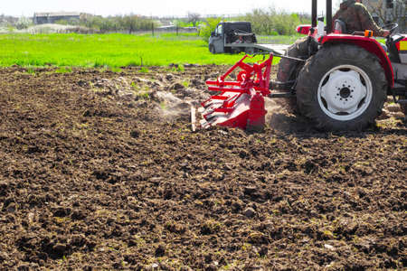 A tractor plows the land in a garden plot on a spring day. Agriculture and Agronomy.の写真素材