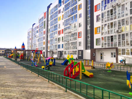 A modern courtyard of a residential high-rise building with a colorful playground. Construction and...