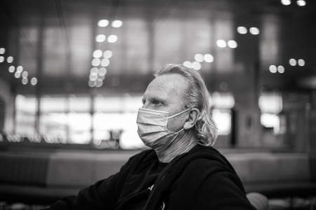 Mature man in a medical mask at the airport waiting for a flight. black and white photography....