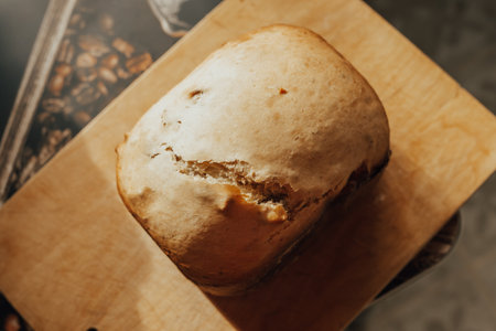 A loaf of fresh fluffy homemade bread baked in a bread machine on a wooden board.の写真素材