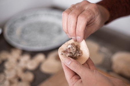A woman in the kitchen sculpts dumplings from dough with meat filling. Cooking delicious homemade dumplings.の写真素材