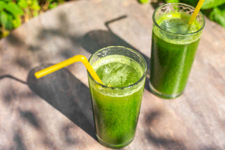 drinks from fresh greens, smoothies from green leaves saturated with chlorophyll on a table in the...