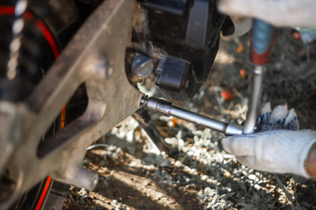 The mechanic unscrews the holder of the rear wheel of the motorbike. Scooter repair and wheel...