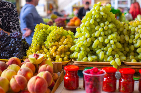 fruit stall. Peaches, green and black grapes on the market. Sale of seasonal fruits.