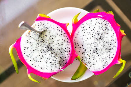 Dragon fruit cut into halves on the table, top view. Delicious healthy juicy tropical dessert.の写真素材