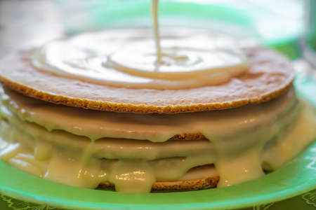 Cooking homemade cake. custard is poured onto the baked cake layers.