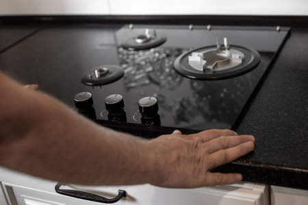 Installation of a gas three-burner built-in stove in a black countertop. kitchen interior.