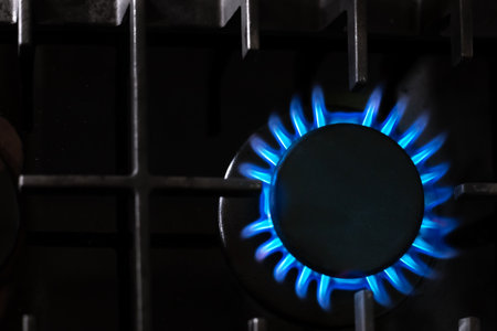 Gas burner with a blue flame on a black kitchen stove, top view, selective soft focus, copy space. gas crisis.の写真素材
