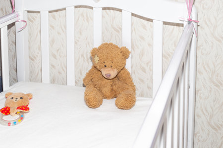 Teddy bear in a white crib.Children's toys, expectation and birth of a child.の写真素材